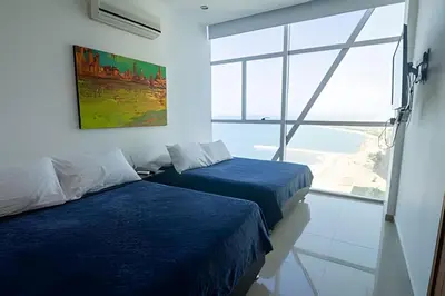 two beds in a room with a large window at Espectacular Vista Al Mar - Edificio Infinito 1802 in Cartagena de Indias