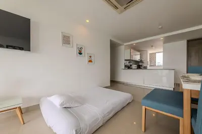 a bedroom with a white bed and a blue stool at Hermoso Apto 2 Hab Piso 19 en Morros City in Cartagena de Indias