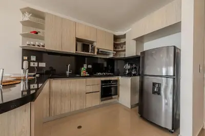 a kitchen with a stainless steel refrigerator and wooden cabinets at Lujoso Apto de 1 Hab en Piso 19- Infinitum in Cartagena de Indias