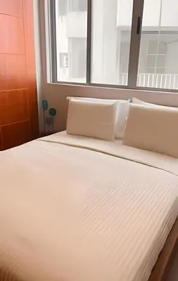 a bed with white sheets and a window at Espectacular Vista Al Mar - Edificio Infinito 702 in Cartagena de Indias