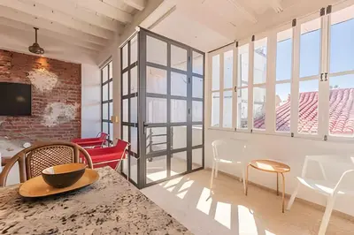 a living room with a table and chairs and windows at El Mirador de la Catedral - Centro Histórico in Cartagena de Indias