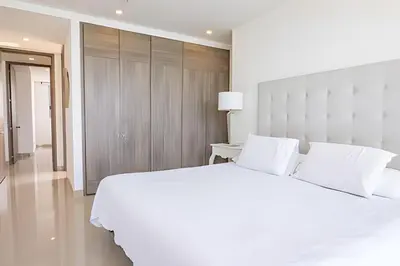 a white bedroom with a large white bed and a table at Espectacular Apto de 2 Hab Piso 24 - Morros City in Cartagena de Indias