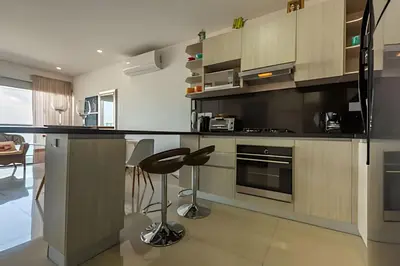 a kitchen with wooden cabinets and a bar with a stool at Infinitum - Spectacular sea view 25th floor apt in Cartagena de Indias