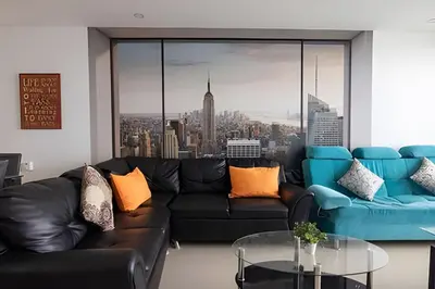 a living room with a black leather couch and a large window at Espectacular Apto de 2 Hab en Piso 27-Morros City in Cartagena de Indias