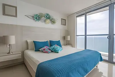 a bedroom with a bed with blue sheets and a window at Lujoso Apto de 1 habitacion en piso 29-Morros City in Cartagena de Indias