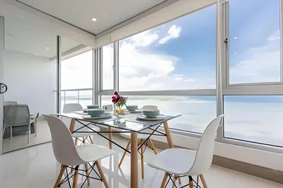 a dining room with a table and chairs and a large window at Palmetto Sunset piso 33 - Vista espectacular in Cartagena de Indias