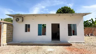 a small white house with a door in a yard at Cabaña Datalu 3 in Coveñas