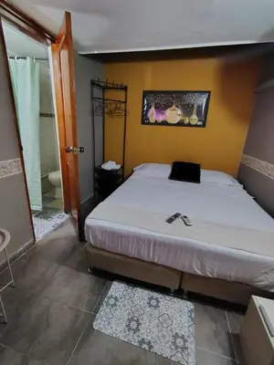 a bedroom with a large white bed and a bathroom at Habitación Privada con Ventilador in Cartagena de Indias