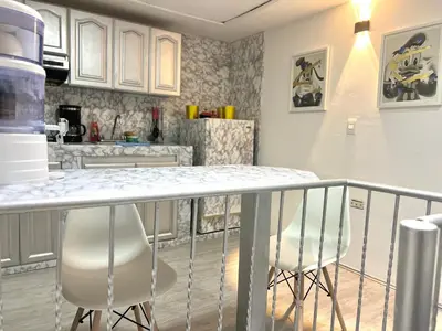a kitchen with a counter and some white chairs at Apartaestudio Cielo Mar A 100 Mts playa - Al Frente Hotel Las Americas in Cartagena de Indias