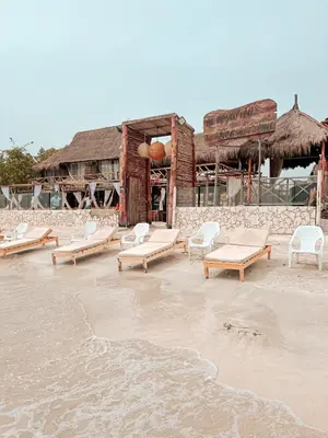 a beach with white chairs and a building at Margarita's Beach Club in Playa Punta Arena