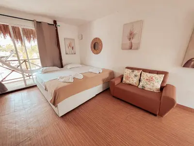 a bedroom with a bed and a couch and a window at Margarita's Beach Club in Playa Punta Arena