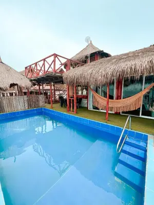 a resort with a blue swimming pool in front of a building at Margarita's Beach Club in Playa Punta Arena