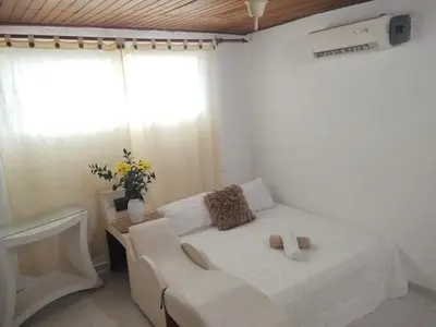 a bedroom with a white bed with a couch and a window at Apartamento en Manga cerca al Centro Historico in Cartagena de Indias