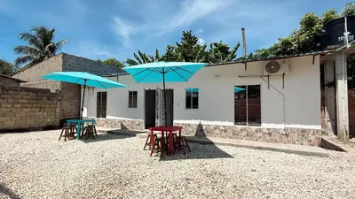 two tables and two blue umbrellas in front of a building at Cabaña Datalu 2 in Coveñas