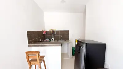 a kitchen with a refrigerator and a table and a chair at Cabaña Datalu 2 in Coveñas