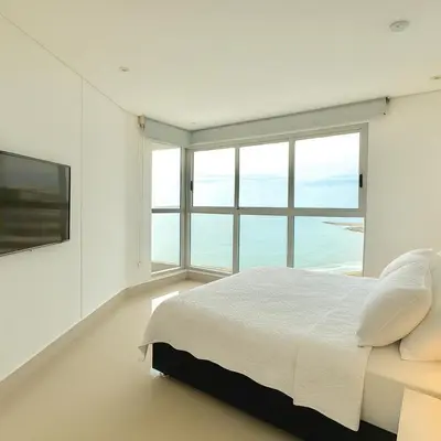 a white bedroom with a large bed and a large window at by Calamari Homes - Murano Elite 1901 Bocagrande in Cartagena de Indias
