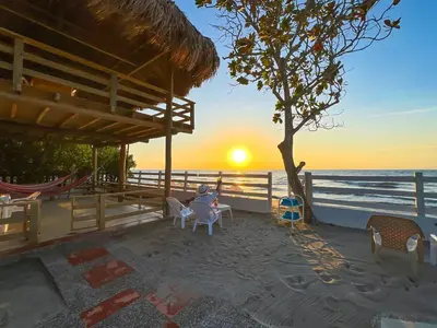 a person sitting in chairs on the beach at sunset at Casa San Miguel Tolú, Playa El Francés in San Silvestre