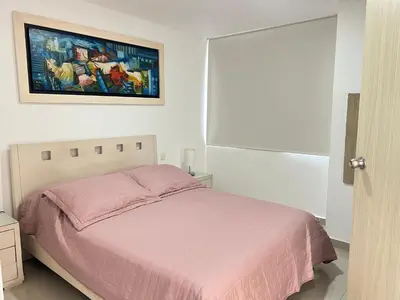 a bedroom with a pink bed and a painting on the wall at Kairos 1209 in Barranquilla