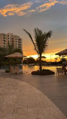 a sunset with a palm tree and chairs and a pool at Apartamento con vistas al mar-SantaMarina-1303 in Santa Marta