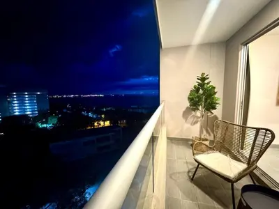 a balcony with a chair and a night view at Apartamento con vista,piscina y playa -SantaMarina-803 in Santa Marta