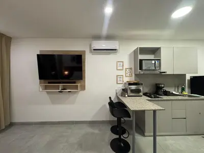 a kitchen with a table and a television on the wall at Apartamento con vista,piscina y playa -SantaMarina-803 in Santa Marta