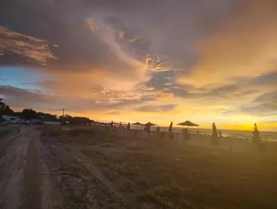a sunset on a beach with umbrellas and the ocean at Exclusive Caribbean Retreat Serena Del Mar in Cartagena de Indias