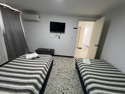 two beds in a room with a tv on the wall at Tarapaca in Barranquilla