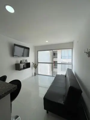 a living room with a black couch and a tv at Apto Amplio con Piscina 3 Hab a Pasos del Mar in Cartagena de Indias