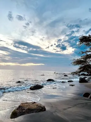 a beach with rocks and the ocean under a cloudy sky at Apartamento Bohemio frente al Mar en Santa Marta in Santa Marta