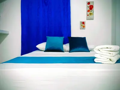 a bed with blue and white sheets and pillows at Hospedaje Torices Cartagena in Cartagena de Indias