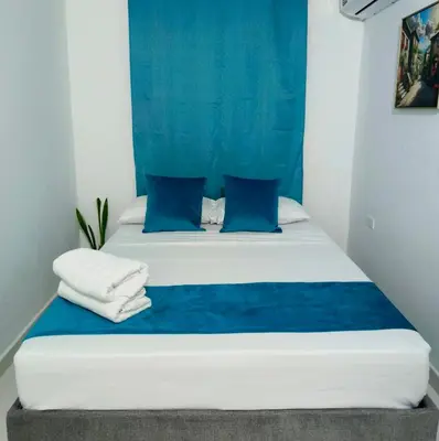 a bed with blue and white sheets and blue pillows at Hospedaje Torices Cartagena in Cartagena de Indias