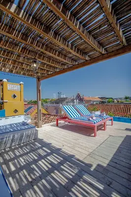 two lounge chairs under awning on a patio at Casa Stella - Authentic Luxury Rooftop Pool in Cartagena de Indias