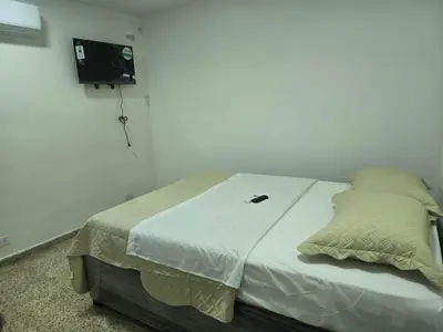 a bed in a room with a tv on the wall at Hotel H&H in Cartagena de Indias