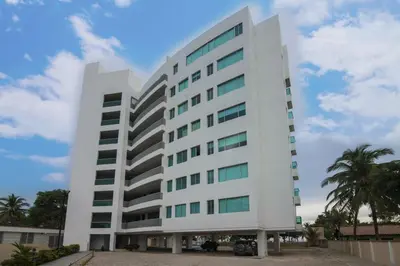 a large white building with a palm tree at Hermoso Apartamento Frente al Mar 3 Habitaciones MSC34 in Estación El Salto