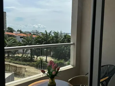 a vase of flowers on a table in front of a window at New luxury studio apartment with ocean view, Santa Marta in Simón Bolivar