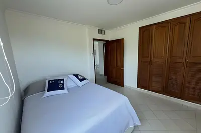 a bedroom with a white bed and wooden cabinets at Apartamento de playa privada in Santa Marta