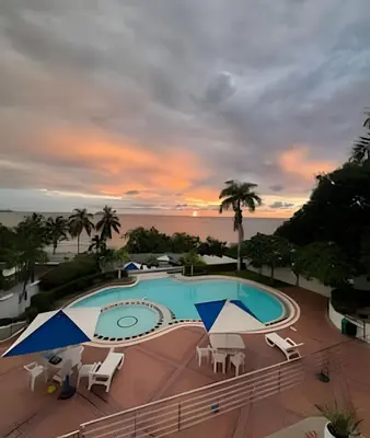 a pool with chairs and umbrellas at sunset at Apartamento de playa privada in Santa Marta