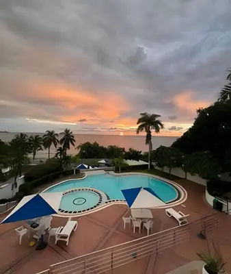 a pool with chairs and a sunset in the background at Alojamiento exclusivo frente al mar in Santa Marta