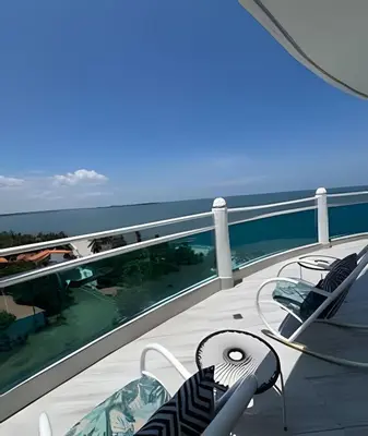 a balcony with chairs and a table and the ocean at Alojamiento exclusivo frente al mar in Santa Marta