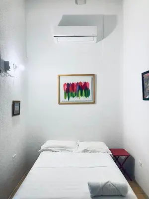 a white room with a bed and a painting of red tulips at Auténtico apartamento en centro histórico con arte in Cartagena de Indias