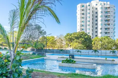 a pool in a park with a building in the background at Apartamentos Exclusivos Santa Marina - AR Rentals in Santa Marta