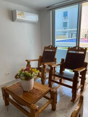 two wooden chairs and a table with a vase of flowers at Teca, Apto , Caribe in Coveñas