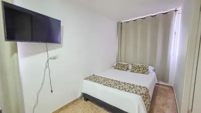 a small bedroom with a bed and a flat screen tv at Apt 3 rooms Laguito Cartagena 1 block from the beach in Cartagena de Indias