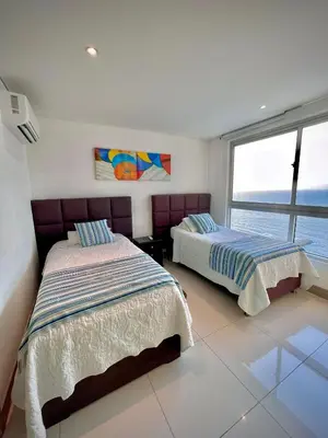 two beds in a bedroom with a view of the ocean at Apartamento de 2 Habitaciones Vista al Mar in Cartagena de Indias