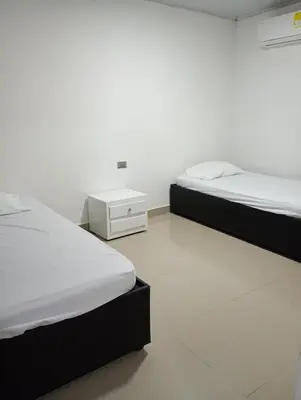 two twin beds in a room with a white wall at Posada mary in Cartagena de Indias