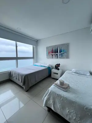 two beds in a white room with a large window at Azurea Beach in Cartagena de Indias