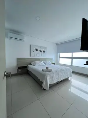 a white bedroom with a bed and a television at Azurea Beach in Cartagena de Indias