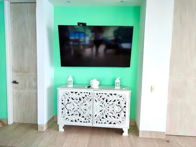 a tv on a green wall with a white cabinet at 3BR AC Amazing View and Pool, Best sunset ever in Coveñas