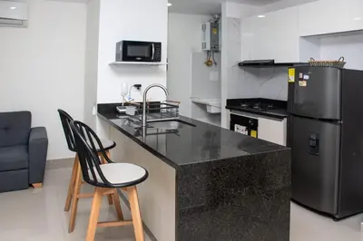 a kitchen with a counter with two chairs and a refrigerator at Hermoso Apartamento con Piscina 1 Habitacion CMC66 in Cartagena de Indias