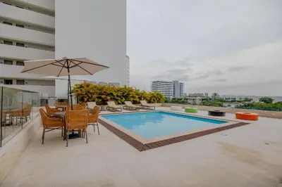 a pool on top of a building with a table and chairs at Encantador y moderno estudio con piscina a pasos del aeropuerto in Cartagena de Indias